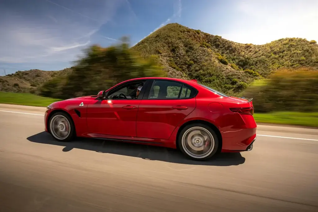 Red sports sedan driving on a scenic highway — ideal photo to represent how easy it is to sell your car fast.